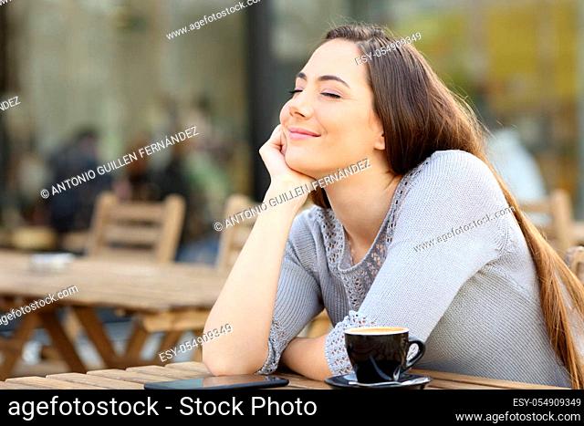 Satisfied woman breathing fresh air on a coffee shop terrace