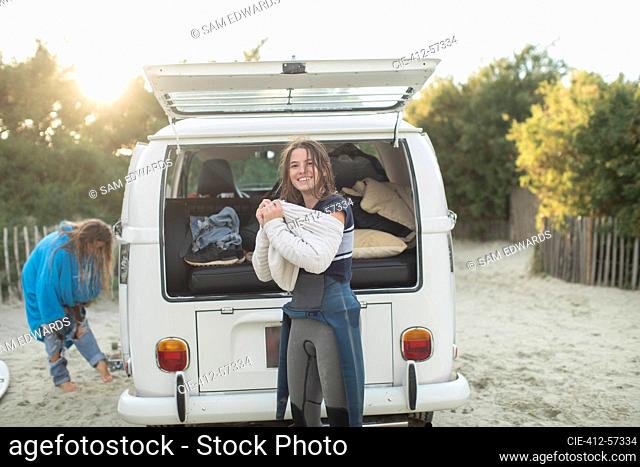 Retrato mujer joven surfista poniéndose suéter en sunny autocaravana