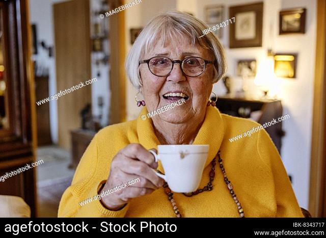 Senior woman at home holding a cup of coffee with a smile, Bocholt, North Rhine-Westphalia, Germany, Europe