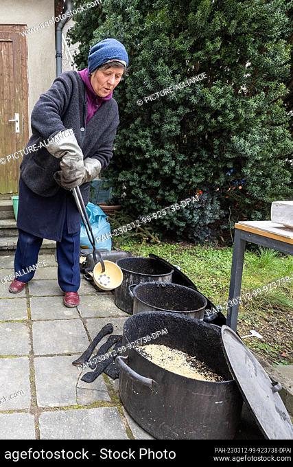12 March 2023, Saxony, Börln: Jana Heistermann takes out fired ceramic bowls from a small kiln, which were made in the raku technique and go into a pot full of...