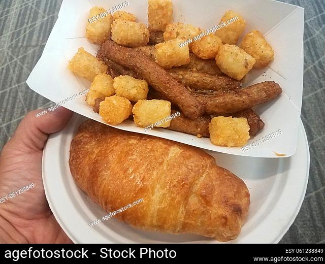 a croissant and sausage and tater tots on a plate