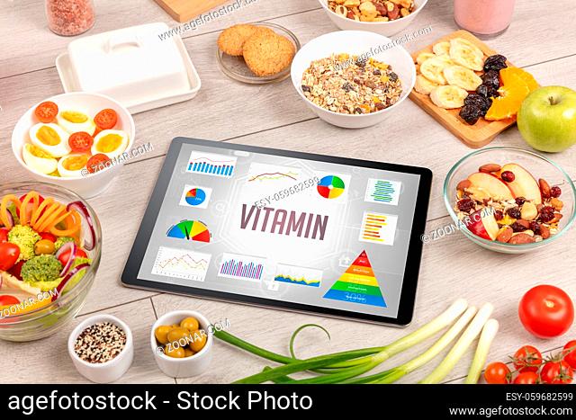 Organic food and tablet pc showing VITAMIN inscription, healthy nutrition composition
