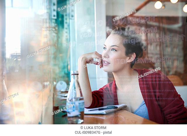 Young woman sitting in cafe, looking out of window