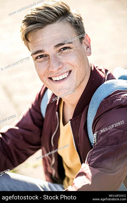 Smiling handsome young man in casuals sitting outdoors