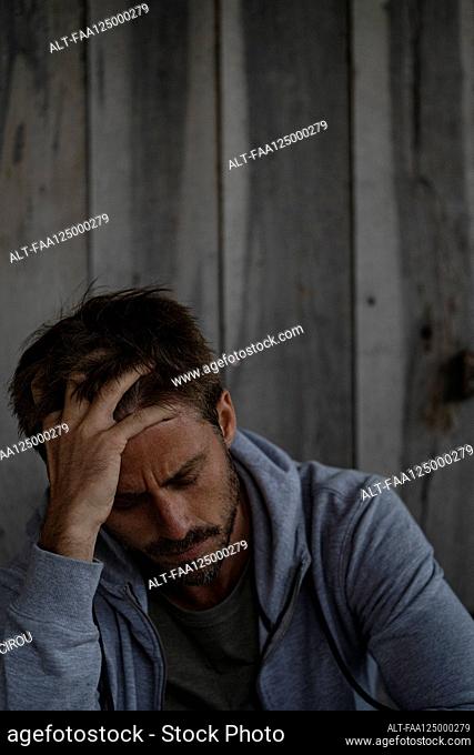 Sad man sitting in stilt hut