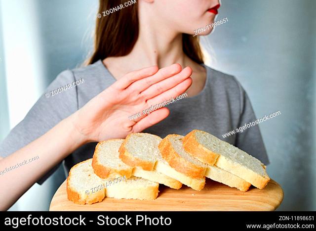 Gluten intolerance concept. Young girl refuses to eat white bread - shallow depth of field - selective focus on bread