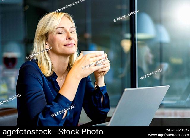 Smiling freelancer with eyes closed sitting at cafe