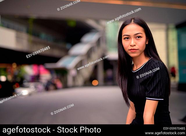 Portrait of young beautiful Asian tourist woman exploring around the city
