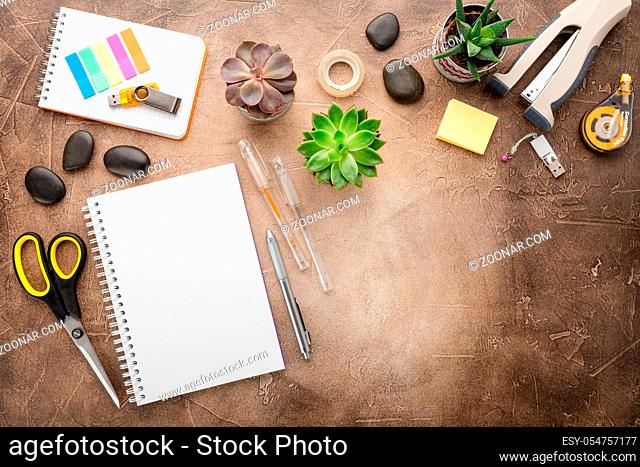 Empty note pad for notes, stationery and pots with succulents on the table. Top view with place for text