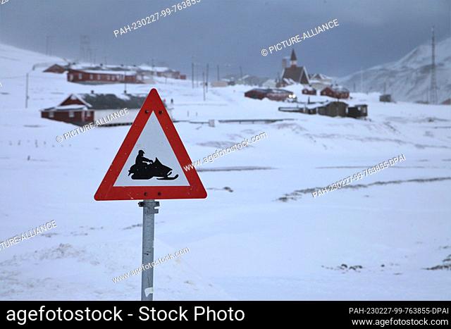 FILED - 27 February 2023, Norway, Longyearbyen: A sign for snowmobiles can be seen in the village on Spitsbergen. Behind it is the local church
