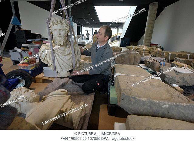 16 April 2019, Baden-Wuerttemberg, Aalen: Restorer Gunther Weinreuter raises the statue of the Roman Emperor Septimius Severus in the Limes Museum