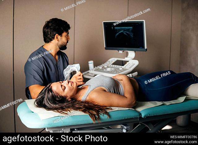 Physiotherapist doing ultrasound to woman on supraspinatus muscle of shoulder