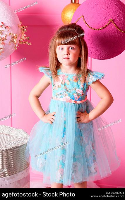 Pretty girl child 4 years old in a blue dress. Baby in Rose quartz room decorated holiday