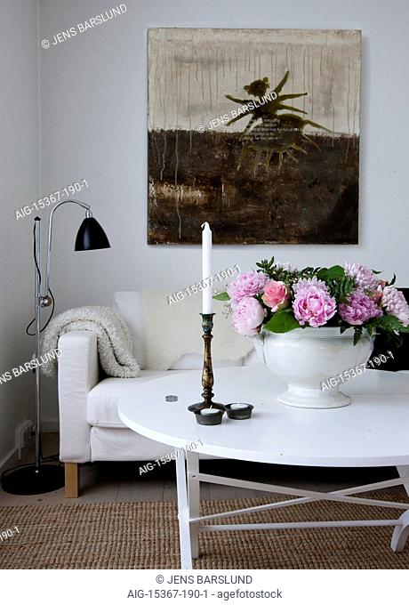 Bright, friendly and cozy, Scandinavia. An open plan space, with white sofa and limed floorboards. flowers in a vase