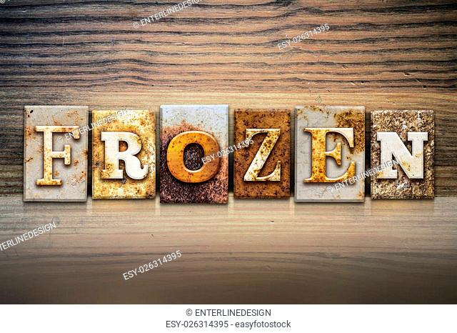 The word ""FROZEN"" written in rusty metal letterpress type sitting on a wooden ledge background