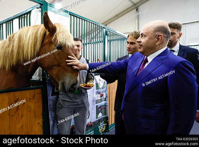 RUSSIA, MOSCOW - OCTOBER 5, 2023: Russia's Prime Minister Mikhail Mishustin (front) pets a horse ahead of a plenary session as part of the 2023 Golden Autumn...