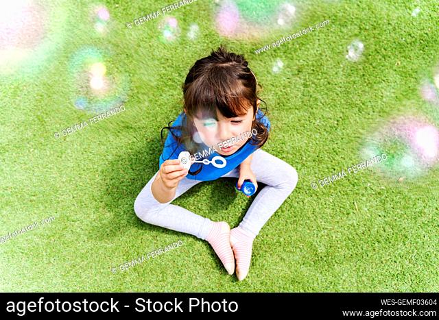 Portrait of little girl blowing soap bubbles