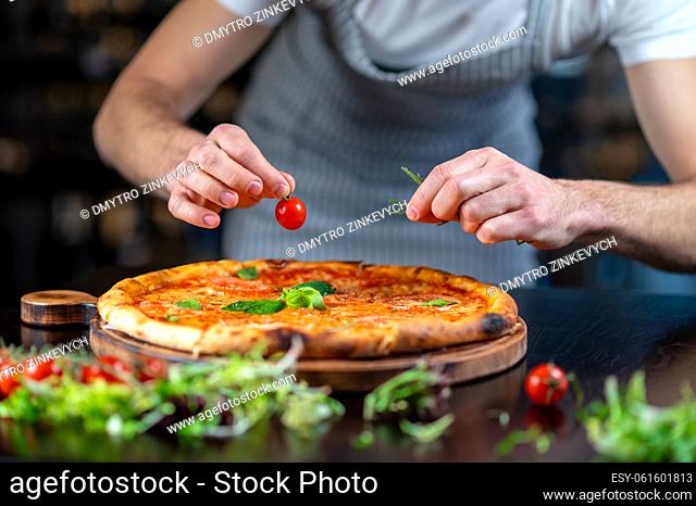 Making pizza. A chef making topping on a italian pizza