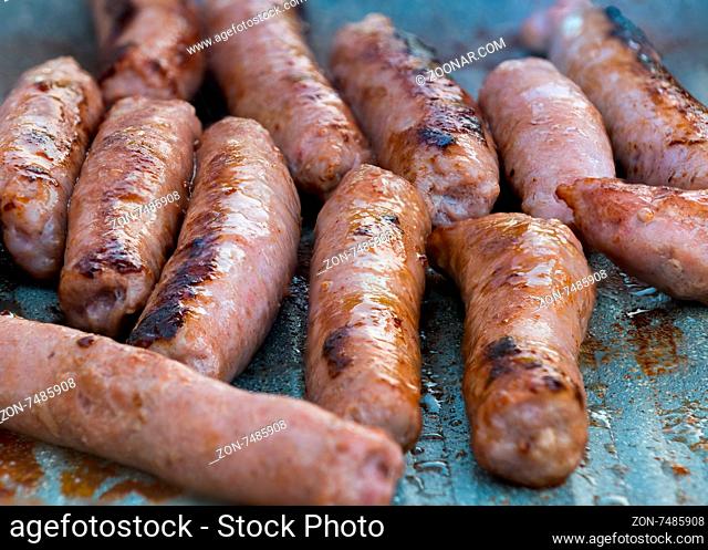 In the picture of the pork sausages are cooked on the grill ( barbecue) while