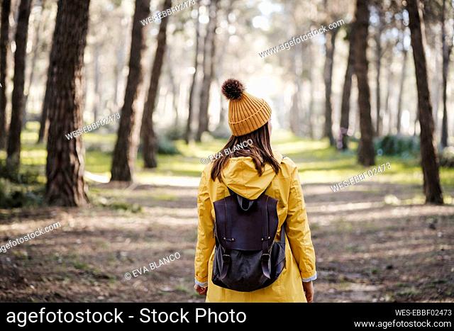 Woman in raincoat standing in forest