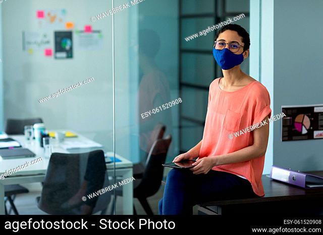 Mixed race woman wearing face mask in an office