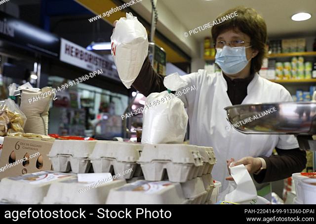 13 April 2022, Spain, Palma: Vendor Aina sells flour to a customer at the Pere Garau market in Palma. After the rise in inflation and the shortage of food due...