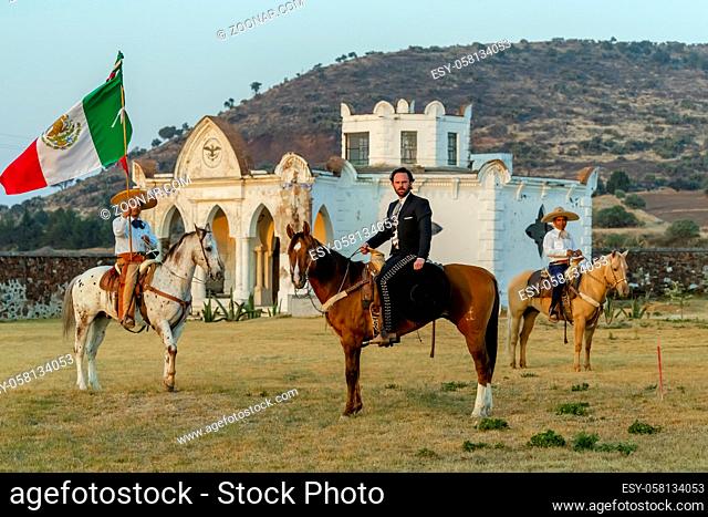 A handsome Mexican Charro poses in front of a hacienda in the Mexican countryside