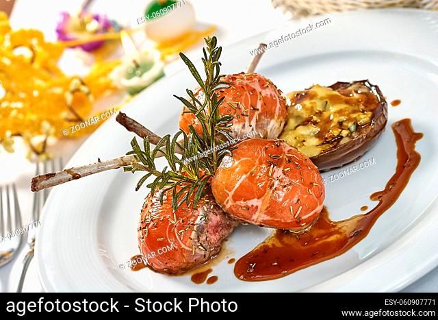 Image of lamb chops on a bed of vegetables Eggplant stuffed with vegetables decorated table romantic dinner