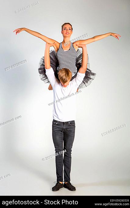 beautiful ballet couple. ballerina in black tutu skirt. man in jeans and white shirt. studio shot. copy space