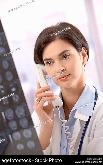 Female doctor looking at x-ray image consulting on phone