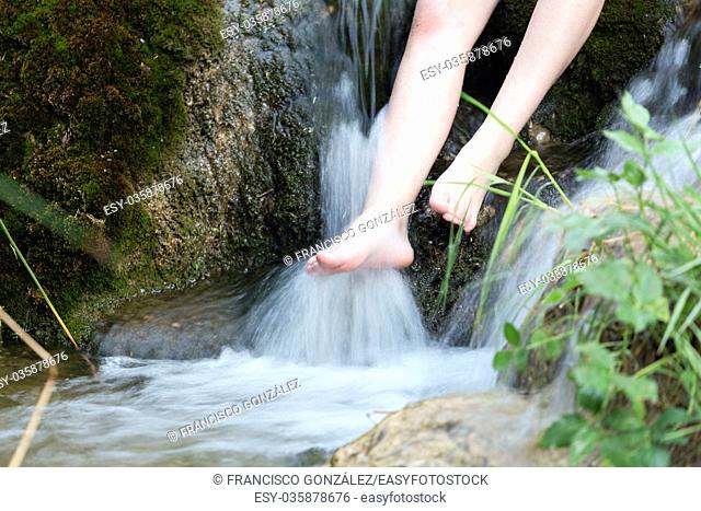 woman wetting her feet in a stream. Take place in Bogarra, province of Albacete, Spain