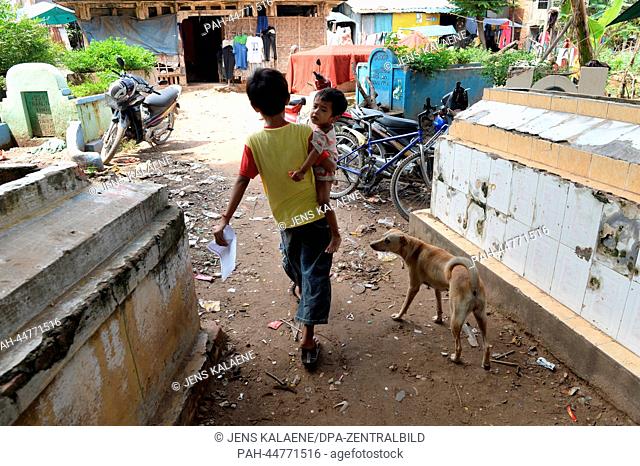 12 year old Sopheak walks with his little brother and a dog in the Chhba Anmpov Slum on the grounds of a Chinese graveyard in Phnom Penh, Cambodia