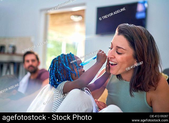 Playful toddler girl with pen writing on mother