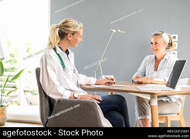 Female doctor talking to patient while sitting at office
