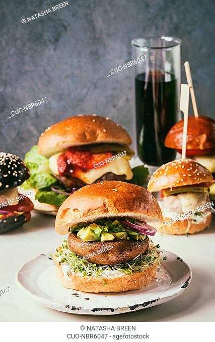 Variety of homemade classic, vegan and mini burgers in wheat and black buns with beef and veal cutlets, portobello mushroom
