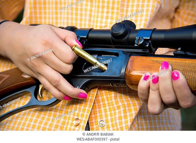 USA, Texas, Young woman inserting bullet in hunting rifle