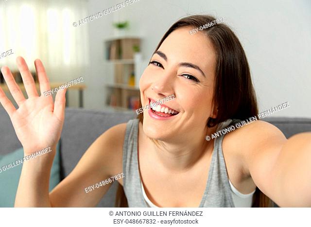 Portrait of a girl waving recording video or taking selfie at home