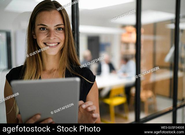 Young businesswoman standing in office, using digital tablet