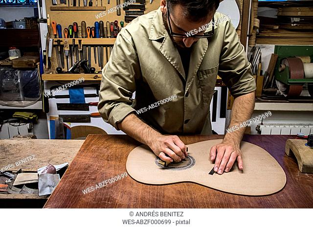 Luthier manufacturing a guitar in his workshop