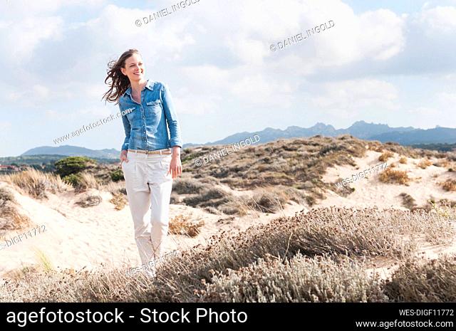 Portrait of happy woman standing in beach dunes, Sardinia, Italy
