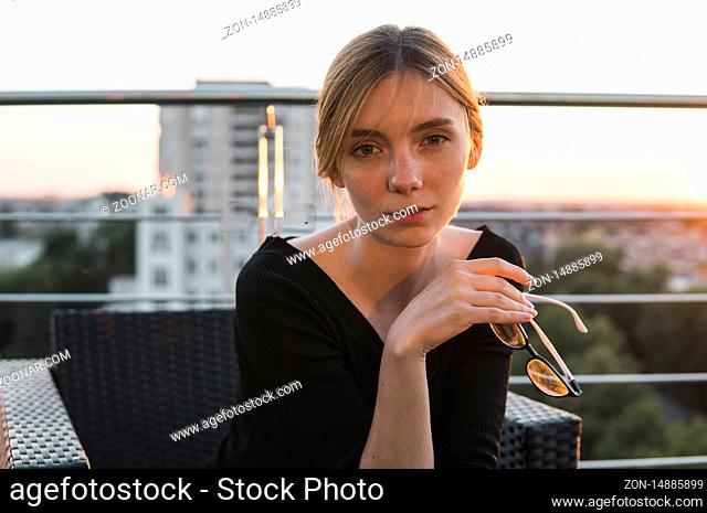 Portrait of a happy and smiling business woman with a sunset sky on background. Portrait of businesswoman sitting on chair in cafe, outdoor