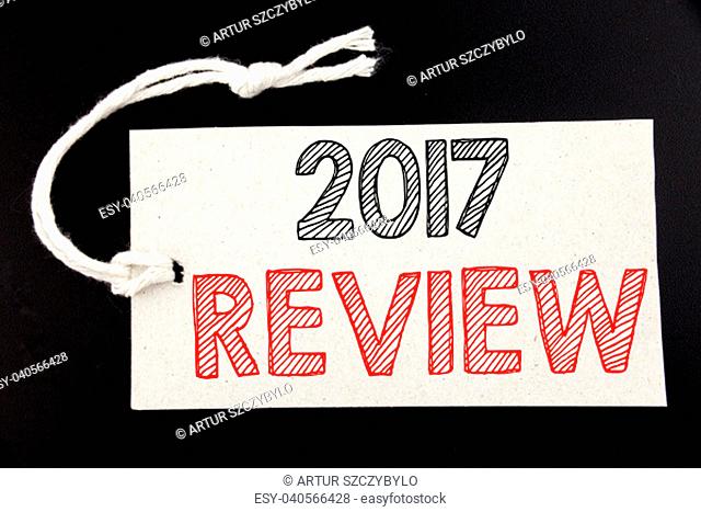 Handwritten text caption showing 2017 Review. Business concept writing for Annual Summary Report written on price tag paper on black vintage background