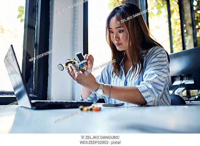 Businesswoman holding model car at desk in office