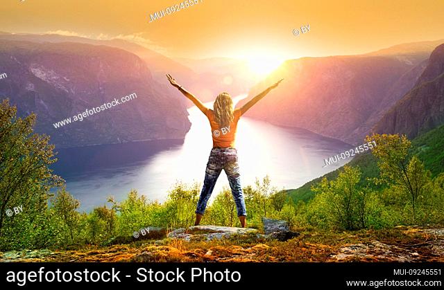 Woman with outstretched arms at sunset at Aurlandsfjord