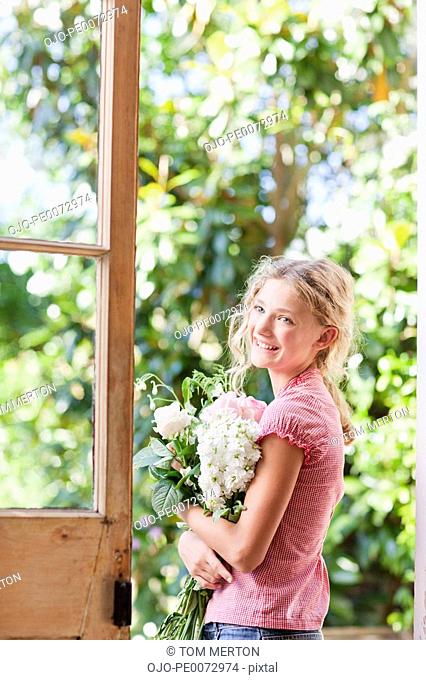 Smiling girl holding bouquet of flowers in doorway