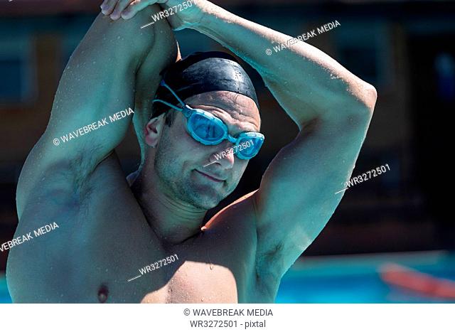 Young man swimmer with swim goggle stretching at swimming pool