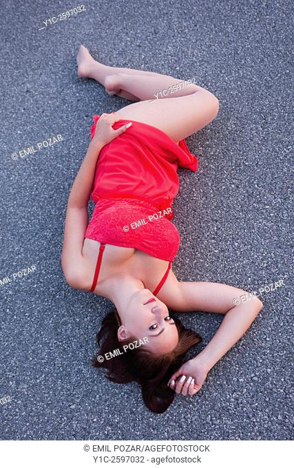 Lying on road in long Red dress young woman