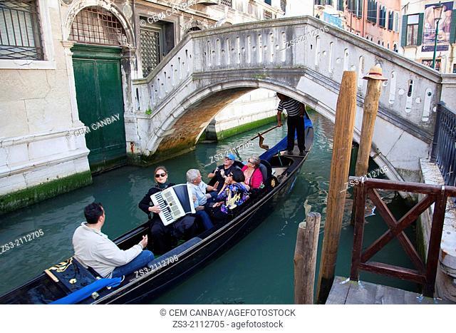 Woman playing accordion on the Gondola in a canal at the backstreet, Venice, Veneto, Italy, Europe