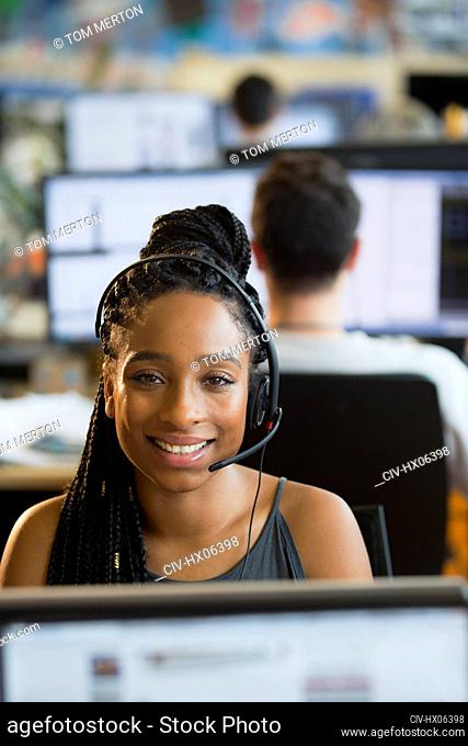 Portrait confident, smiling businesswoman with headset working in office
