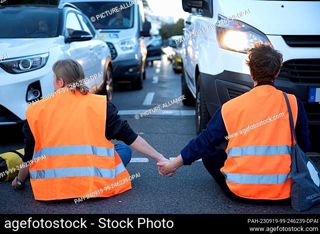 19 September 2023, Berlin: Activists of the climate protection group Letzte Generation hold hands during a street blockade on Mehringdamm